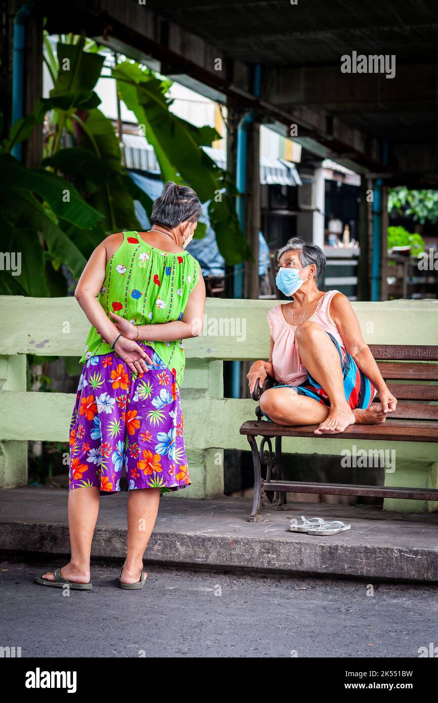 Two Thai ladies chat in the tight streets and lanes of the Ruamrudee area near to Lumpini Park Bangkok Thailand. Stock Photo