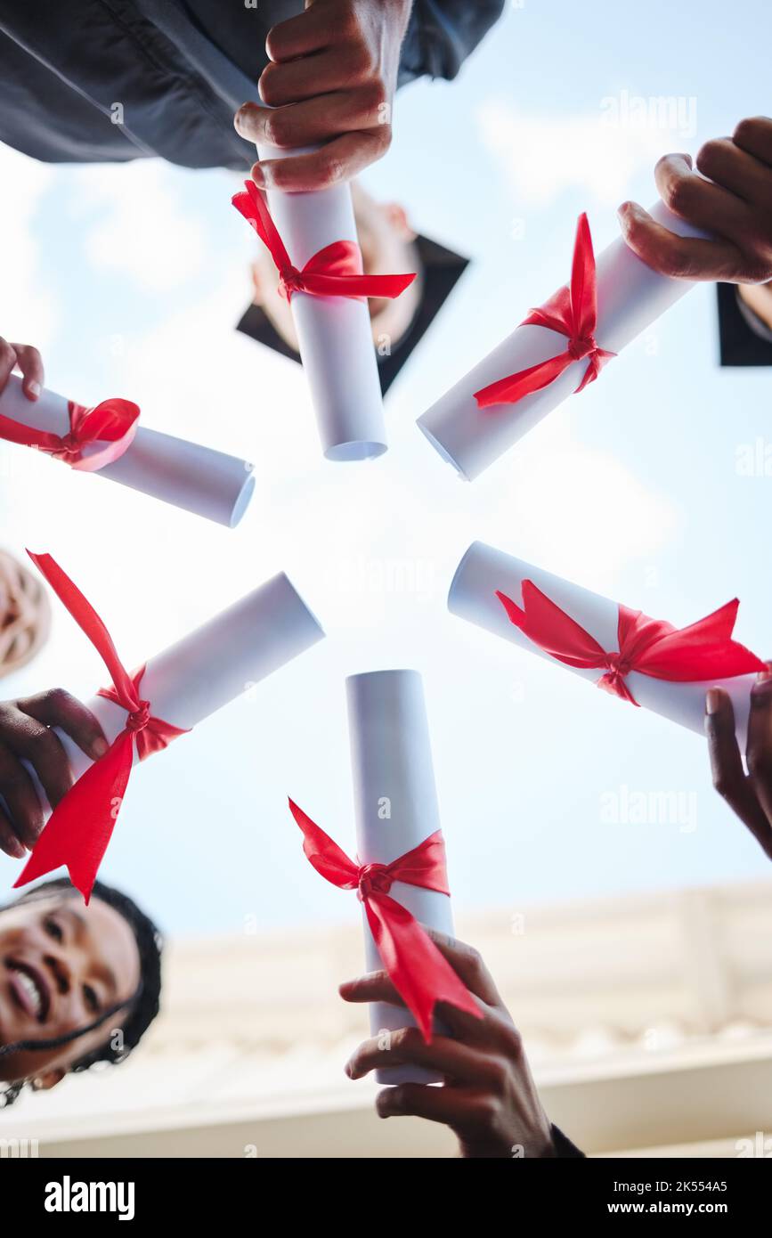 Graduation, diploma and hands with a student group outside in a huddle or circle from below. Graduate, success and university with friends holding a Stock Photo