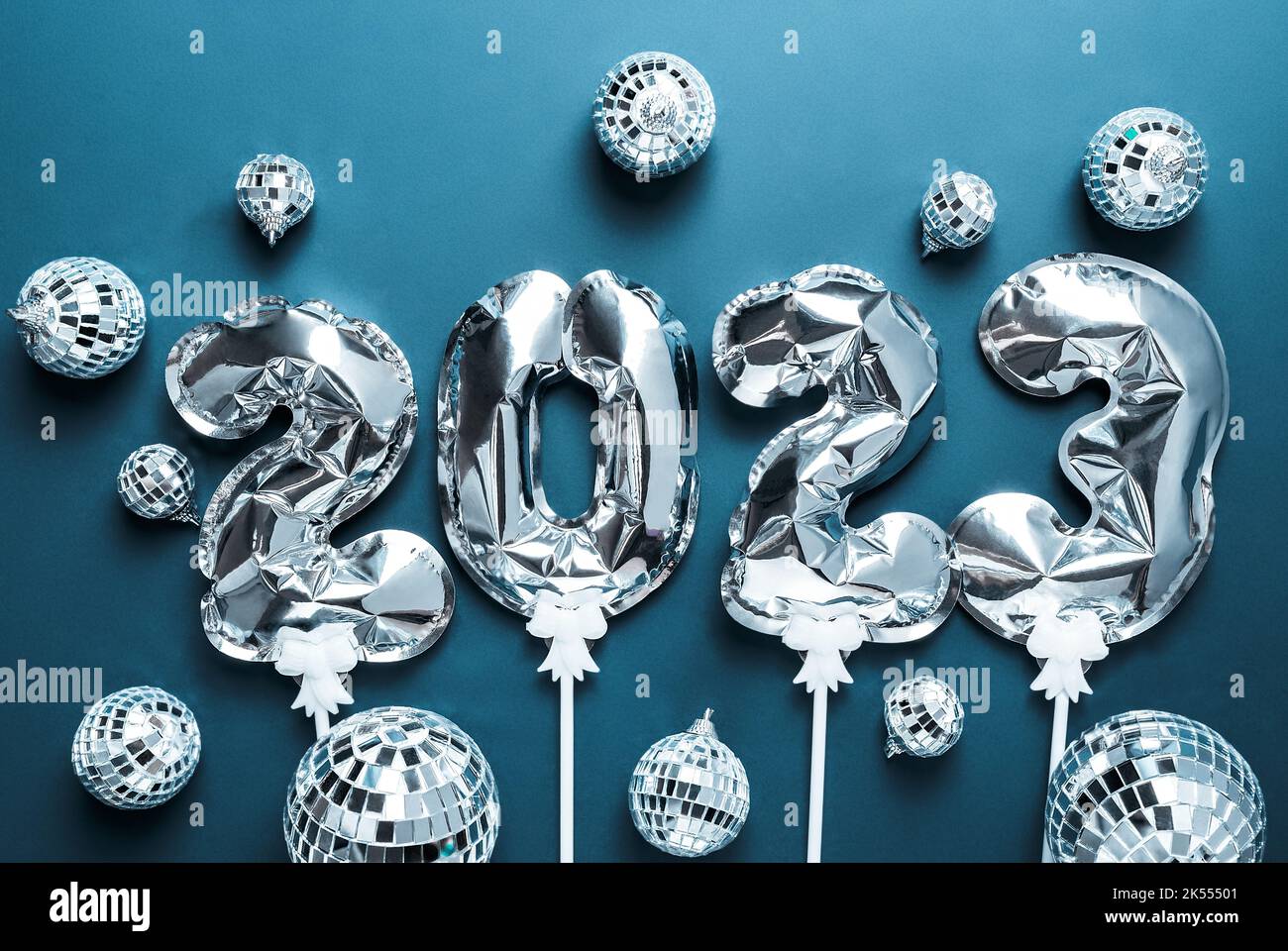 Happy New Year 2023. silver foil balloons and disco balls on blue background. Festive concept. Flat lay, top view, Stock Photo