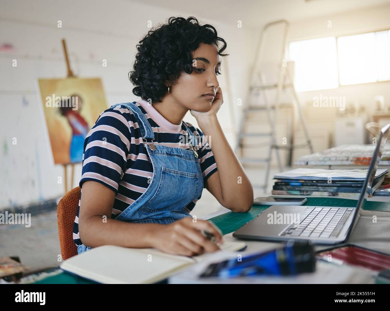 Thinking woman, laptop and writing notes for online art business with freelance artist in studio, workshop or showroom busy working on the internet Stock Photo