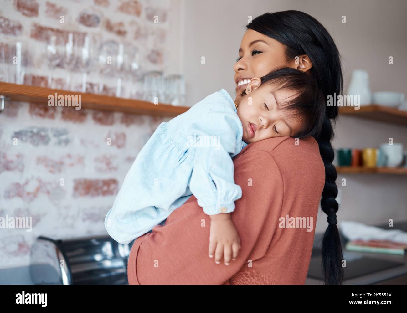 Care, love and mother holding sleeping baby with down syndrome in the kitchen of their house. Newborn child with development problem sleep with happy Stock Photo