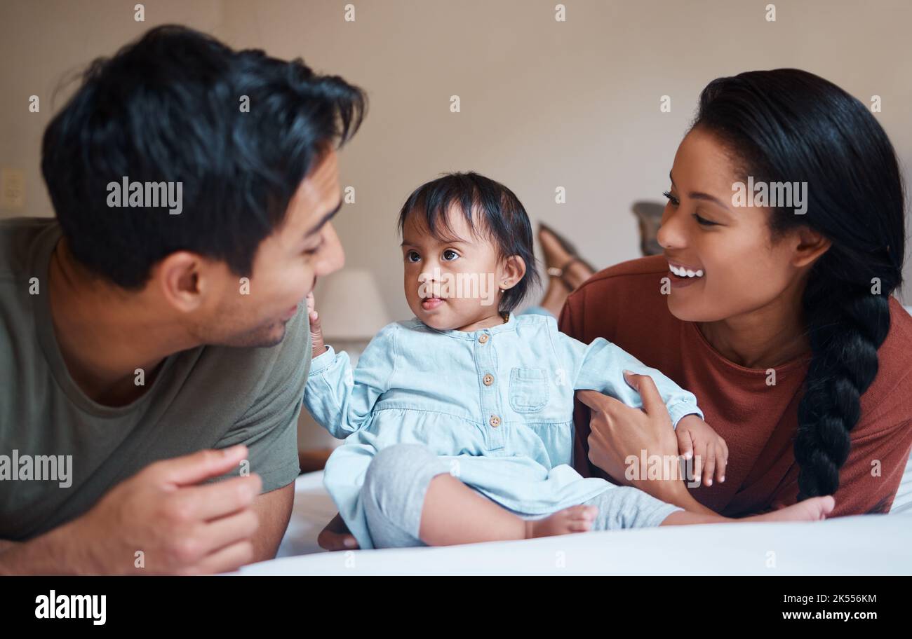 Down syndrome, mother and father bonding with child smile, happy and together at home for quality time. Family, man and woman with baby, kid and Stock Photo