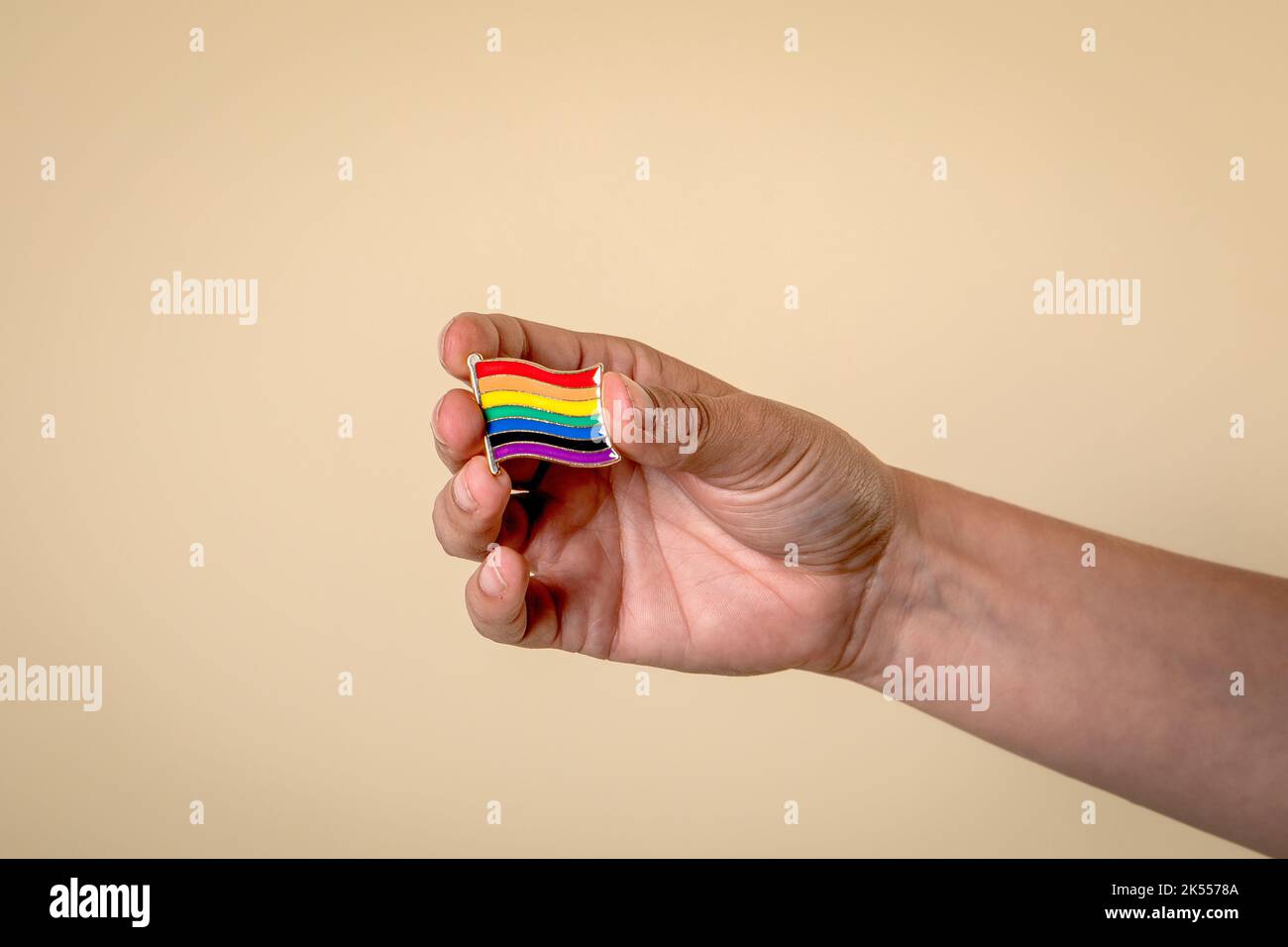 Rainbow colored miniature flag pin in woman's hand. Stock Photo