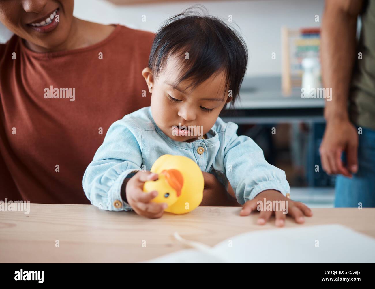 Sleeping, disability and baby with down syndrome after playing with toy asleep on his mothers lap in family home. Mama, exhausted and tired child with Stock Photo