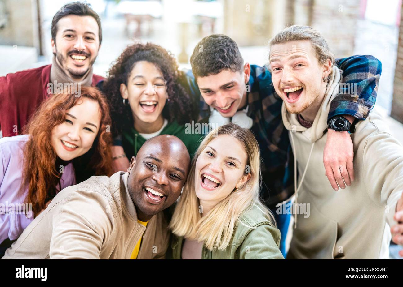 Multicultural guys and girls taking selfie outdoor on urban background - Happy milenial life style concept with young multiethnic trendy people having Stock Photo