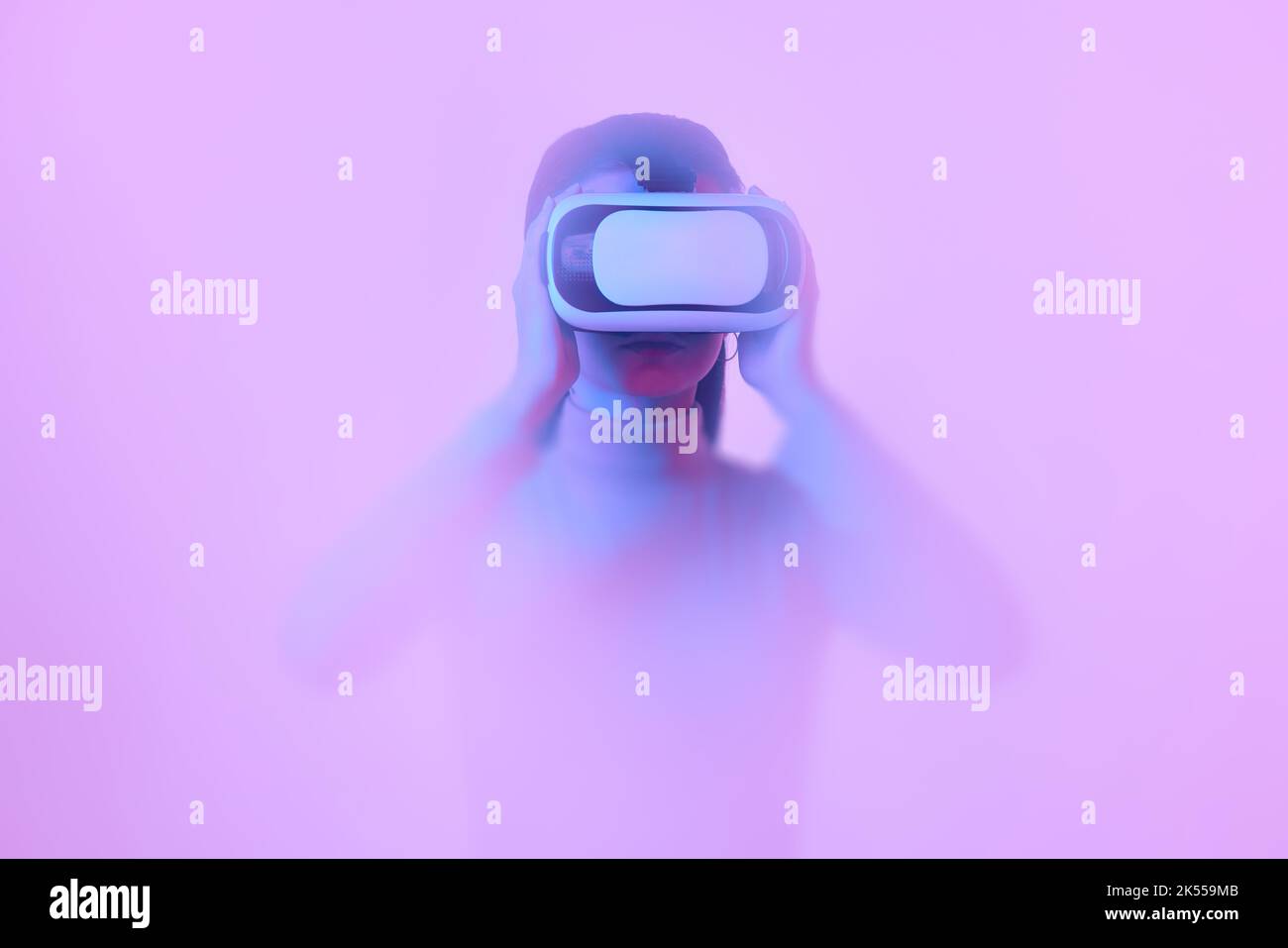 Young girl wearing VR headset immersed in backlit diffuse liquid. Concept of art, metaverse, modern technology, video games and virtual reality Stock Photo