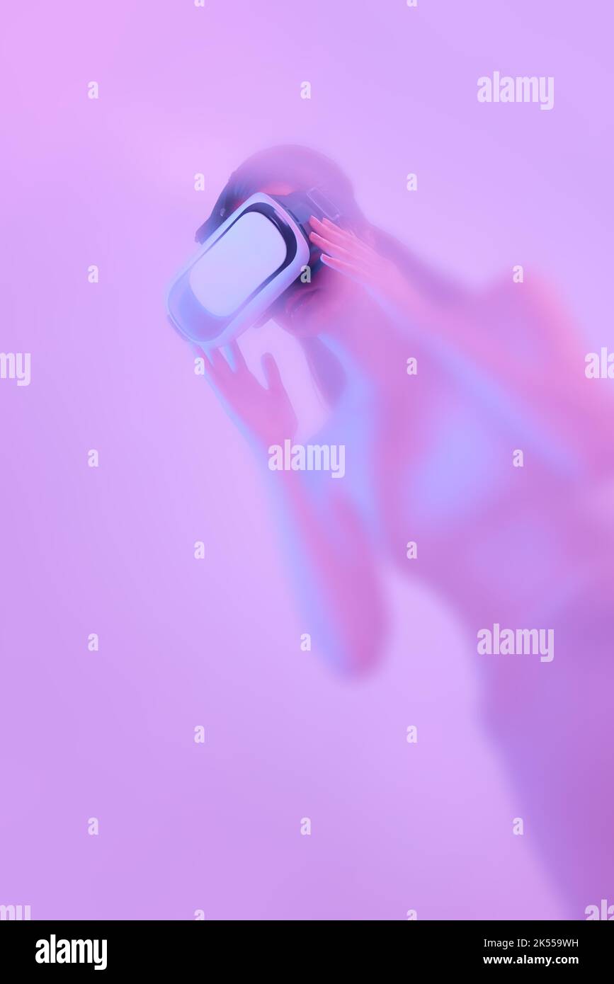 Female model in virtual reality glasses, immersed in clouds of smoke, fog on a pink neon background with a backlight diffuser. Stock Photo