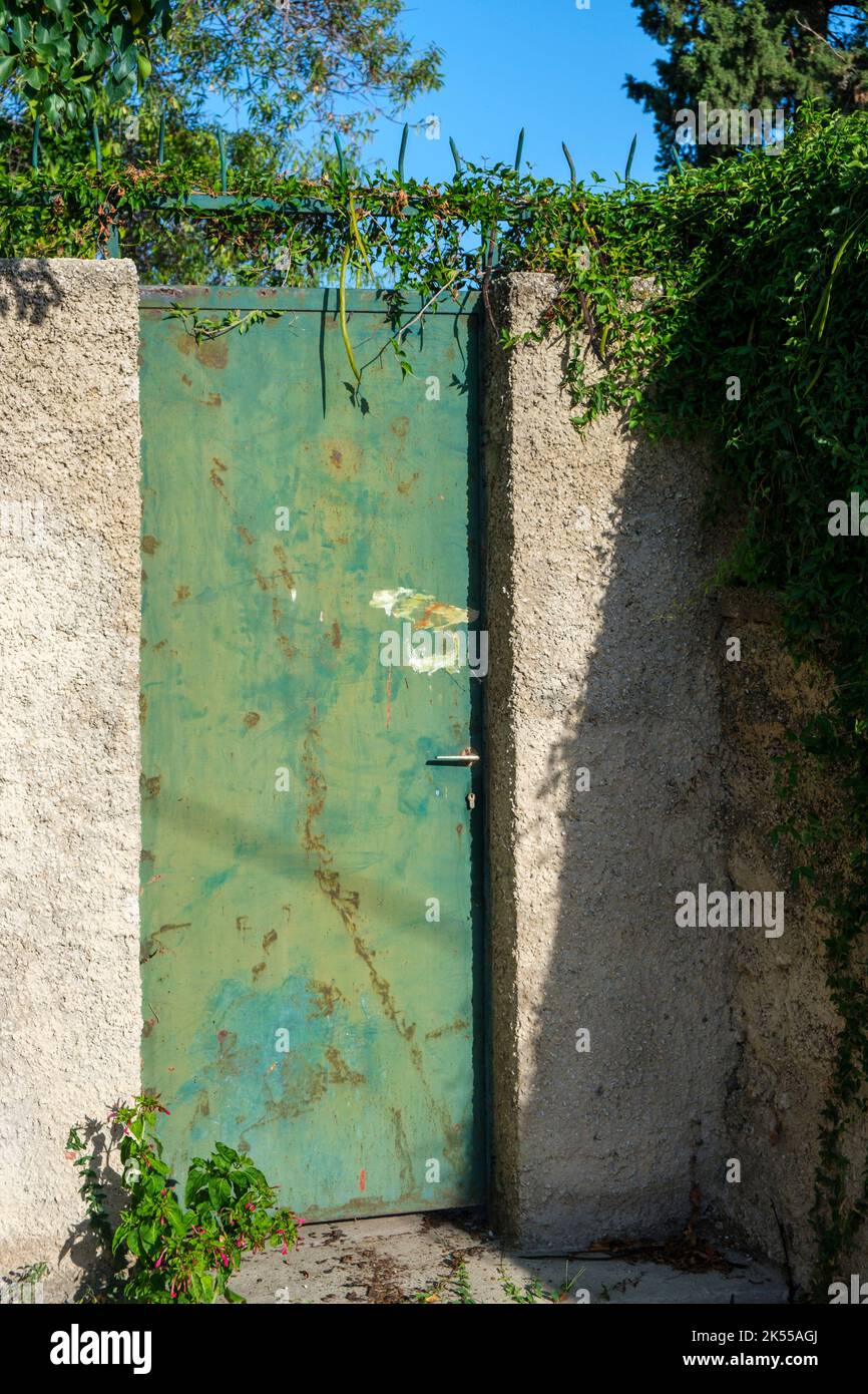 Old gate, rusty and weathered leading to properties that look alittle run down. Stock Photo