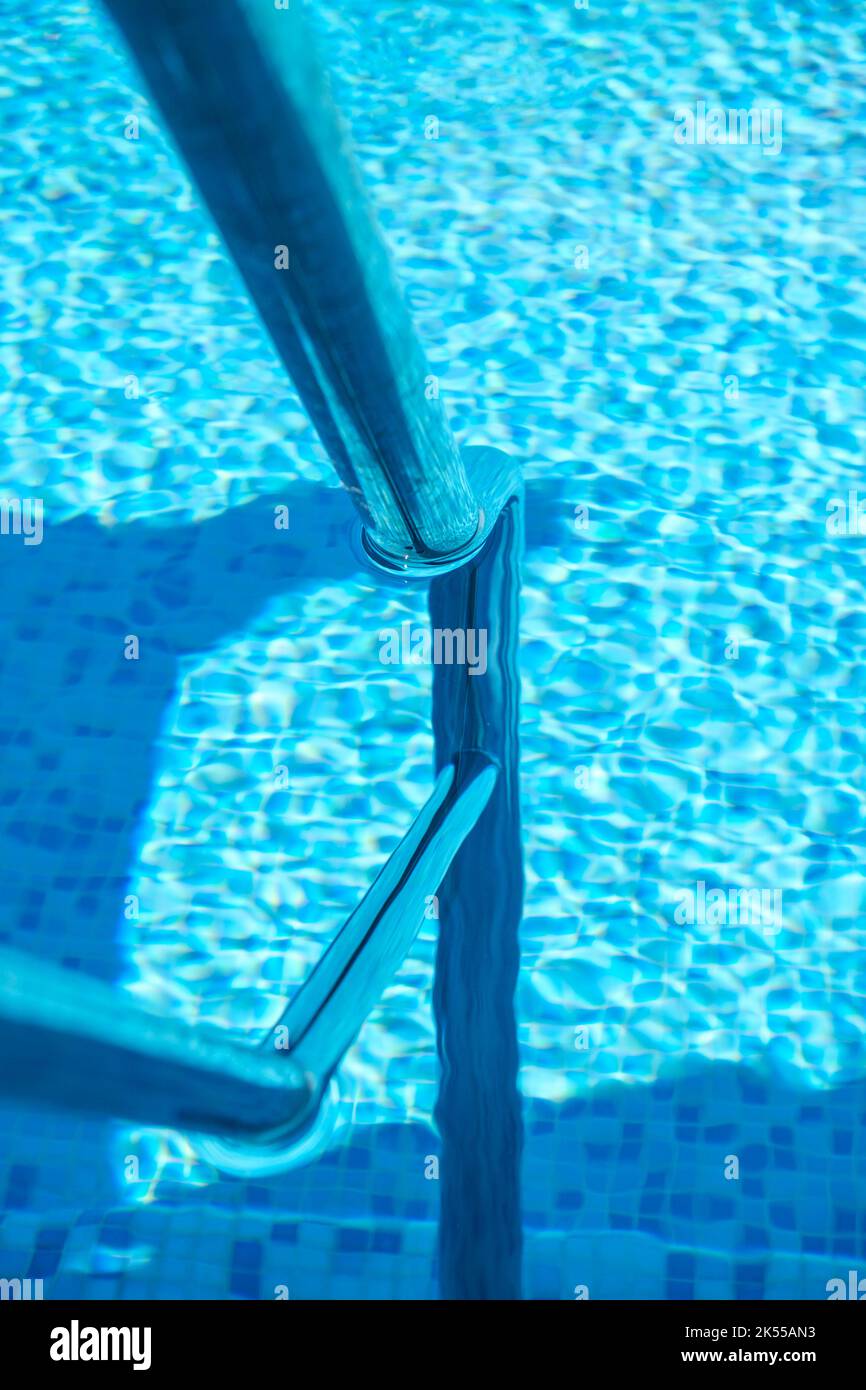 A deep blue swimming pool with steel rail to help entry and exit Stock
