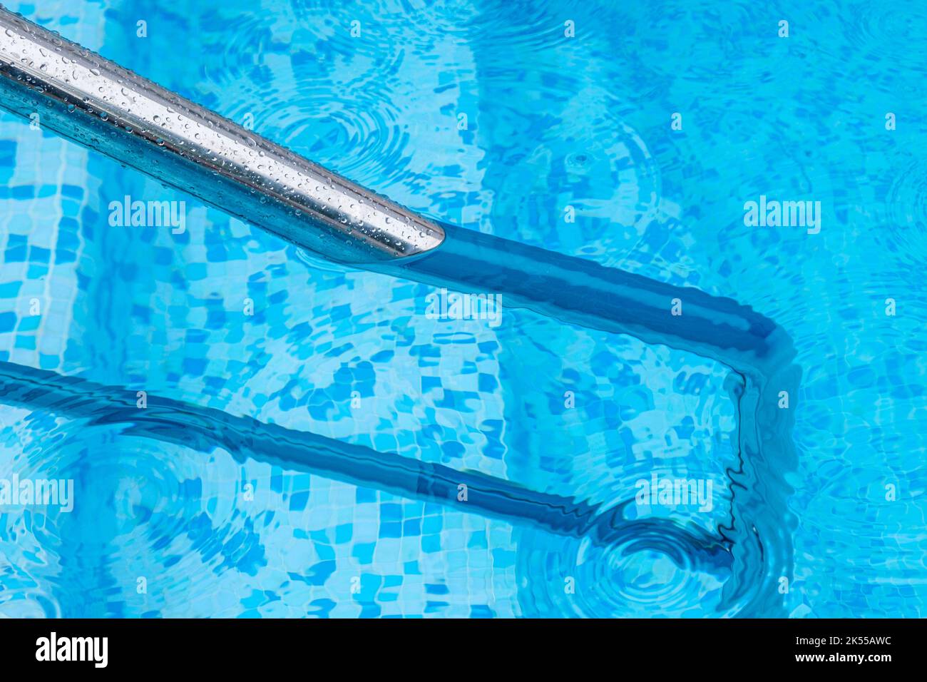 A deep blue swimming pool with steel rail to help entry and exit Stock
