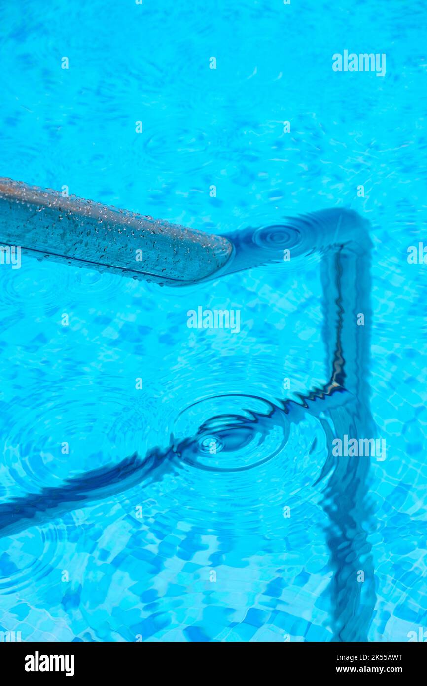 A deep blue swimming pool with steel rail to help entry and exit Stock