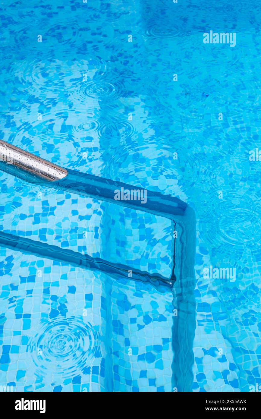 A deep blue swimming pool with steel rail to help entry and exit Stock