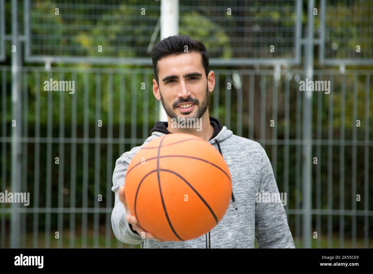 Selective focus on the smiley face of a man with a basketball ball in a  court Stock Photo - Alamy