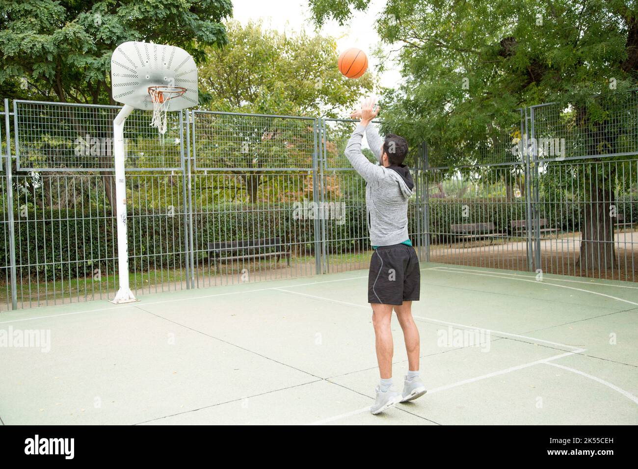 Man throwing a ball from the three-point line on an outdoor basketball ...