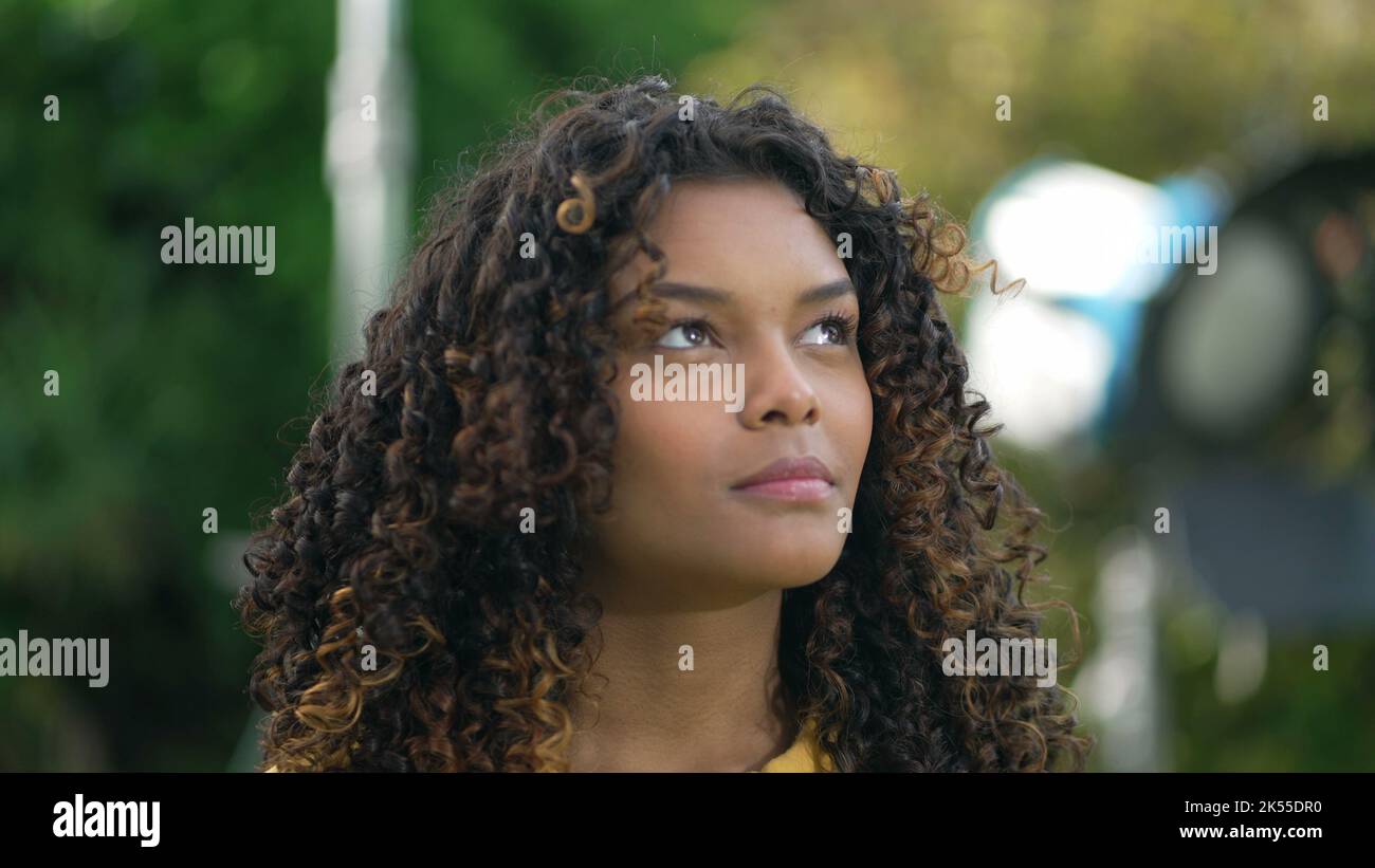 One black young woman looking up at sky smiling with