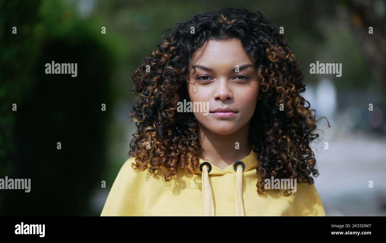 One confident young black latina girl walking forward toward camera.  African American 20s millennial woman with curly hair walks in street Stock  Photo - Alamy, image size:1300x821