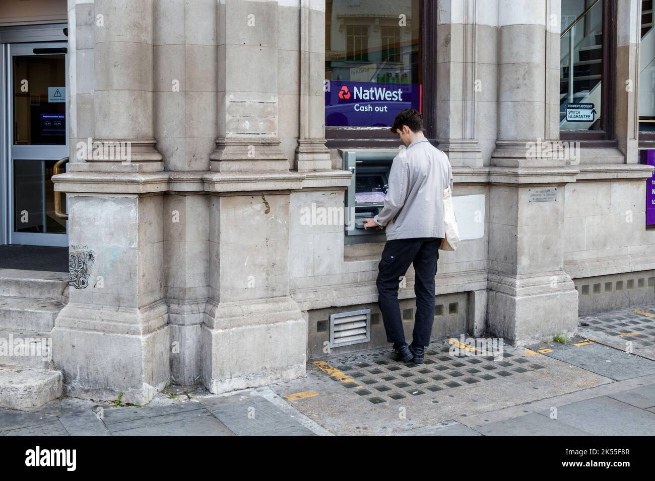 A man uses the ATM at a branch of NatWest bank in Camden Town, London, UK Stock Photo