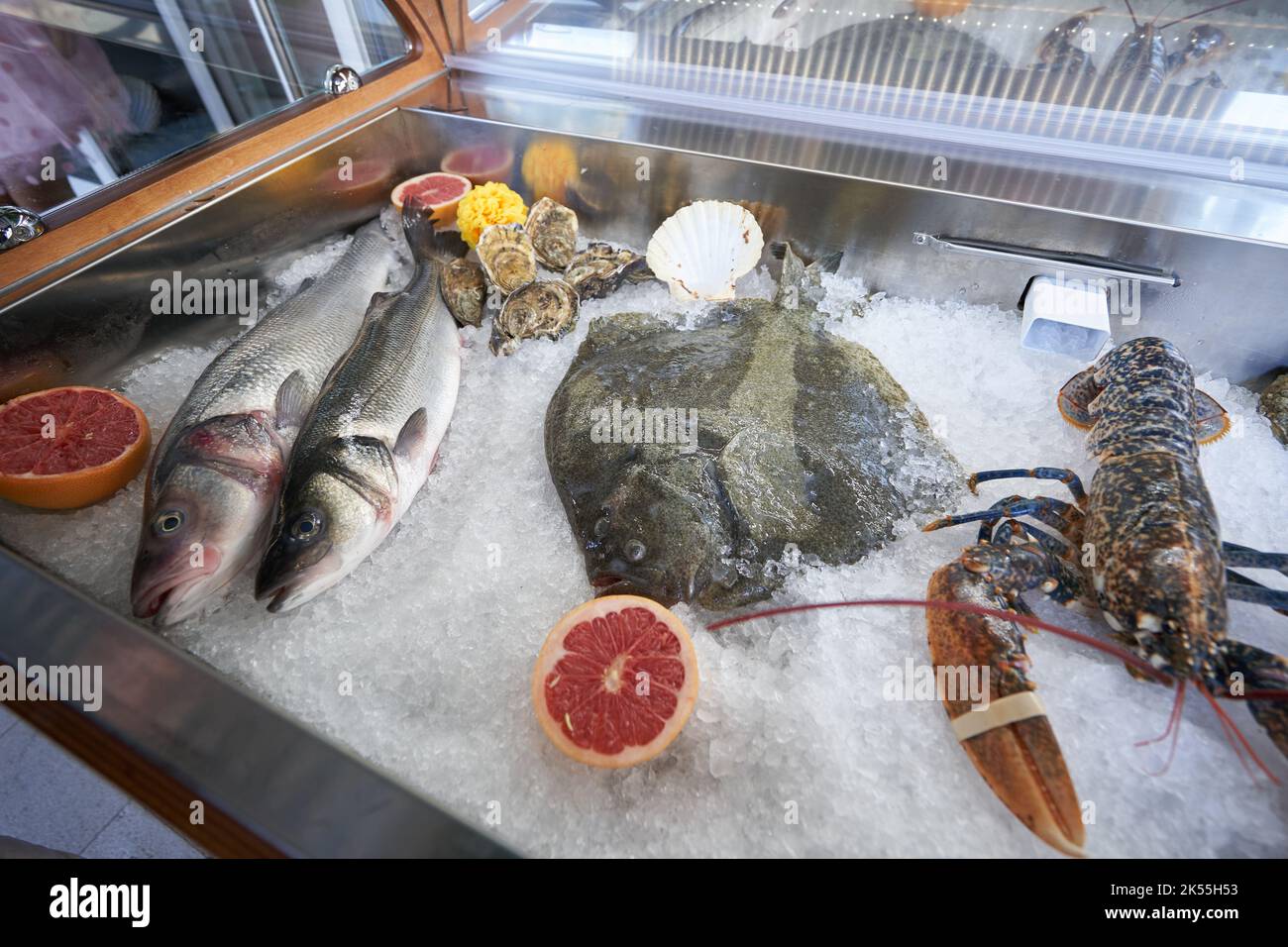 Fresh fish lie on ice in the display fridge. Stock Photo