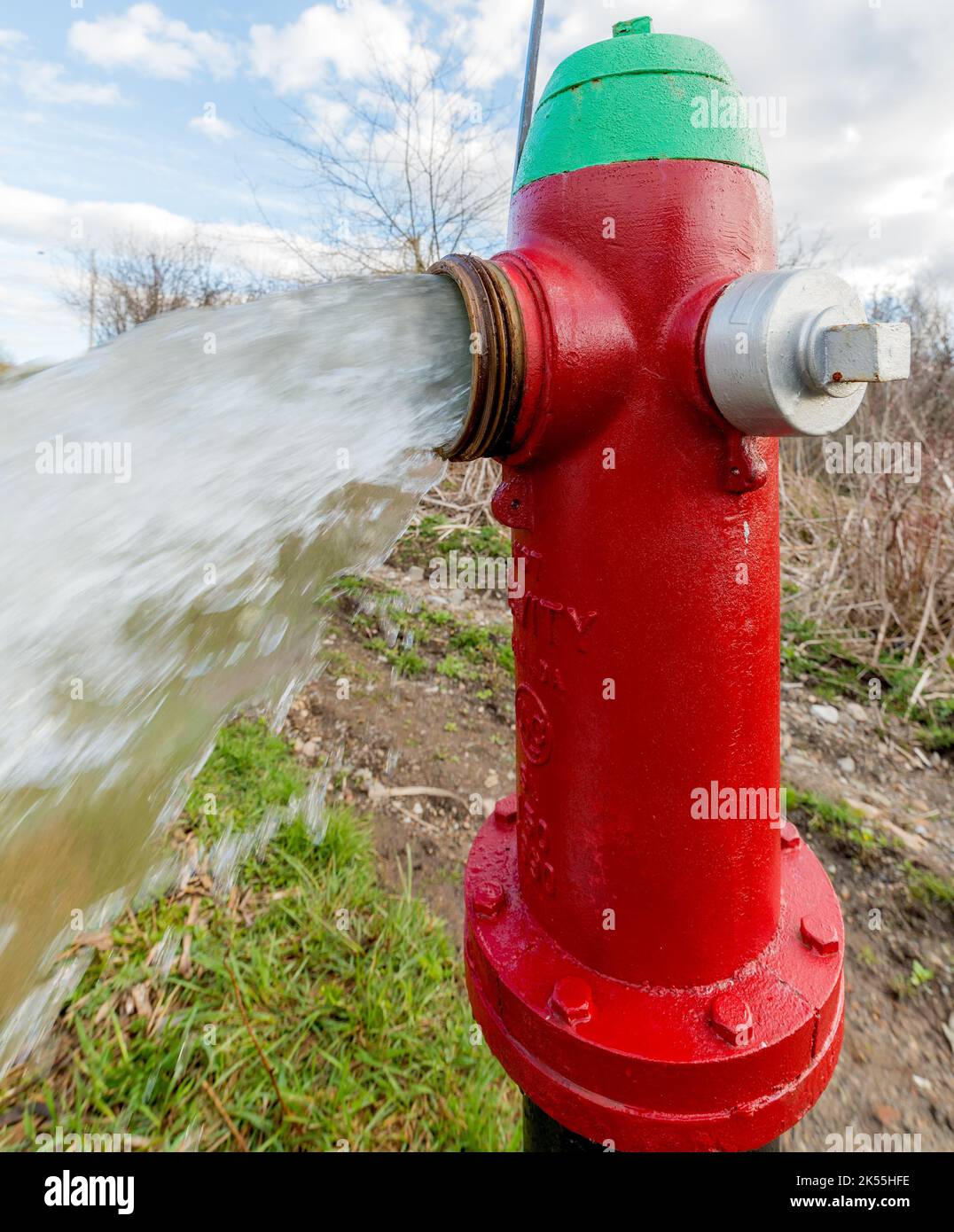 Water flowing from an open red fire hydrant. Closeup side view. The top