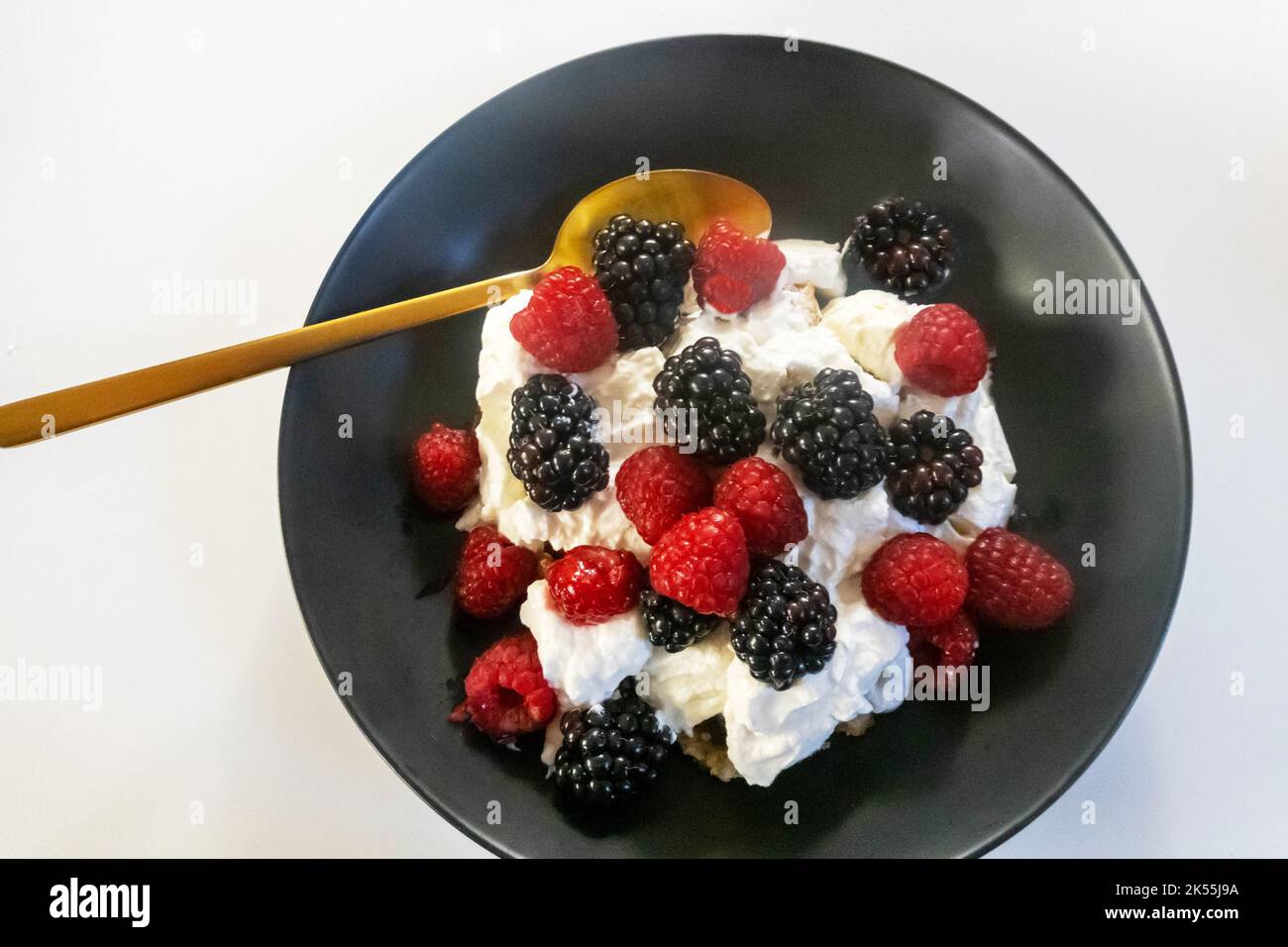 Blackberries and raspberries with Greek yogurt in a black bowl Stock Photo