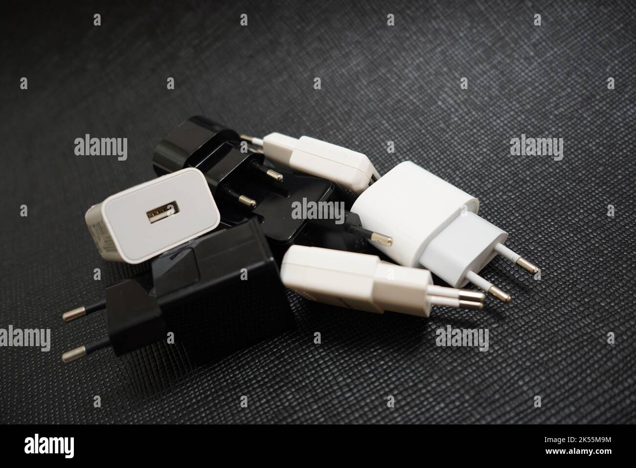 many phone charger adapters of different types on a black background
