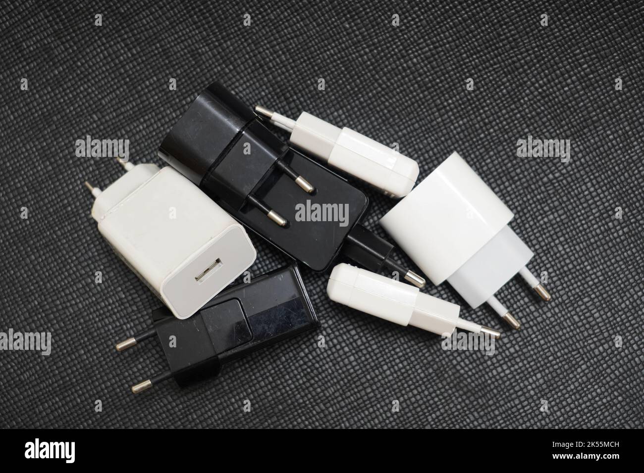 many phone charger adapters of different types on a black background