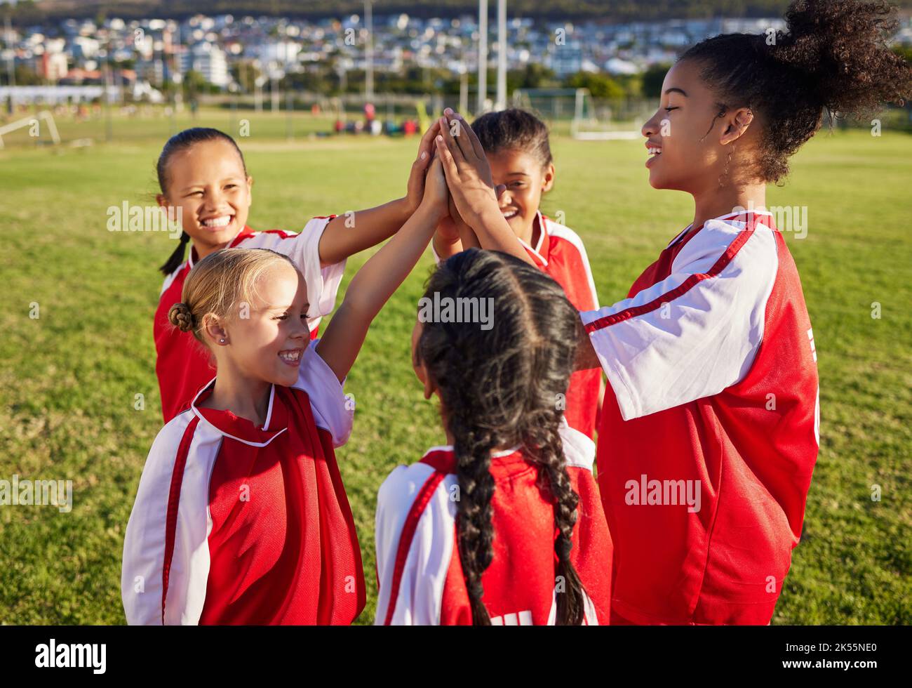 Children, girl football team and high five for sports group motivation on a soccer field for celebration of goal, winning and teamwork outdoors Stock Photo