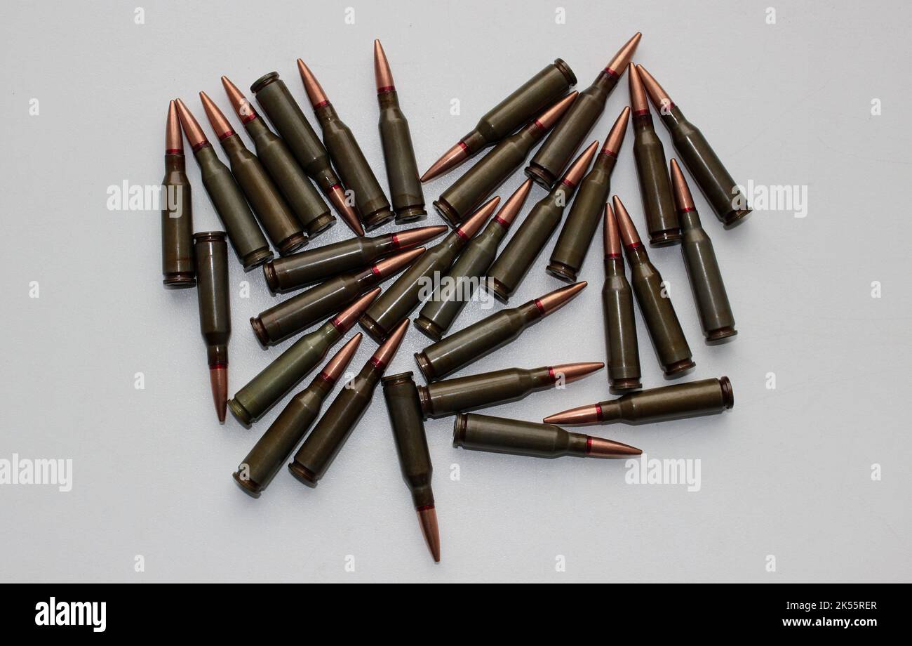 Unitary cartridges with copper alloy shell bullets for assault rifle scattered on a whire surface top view Stock Photo
