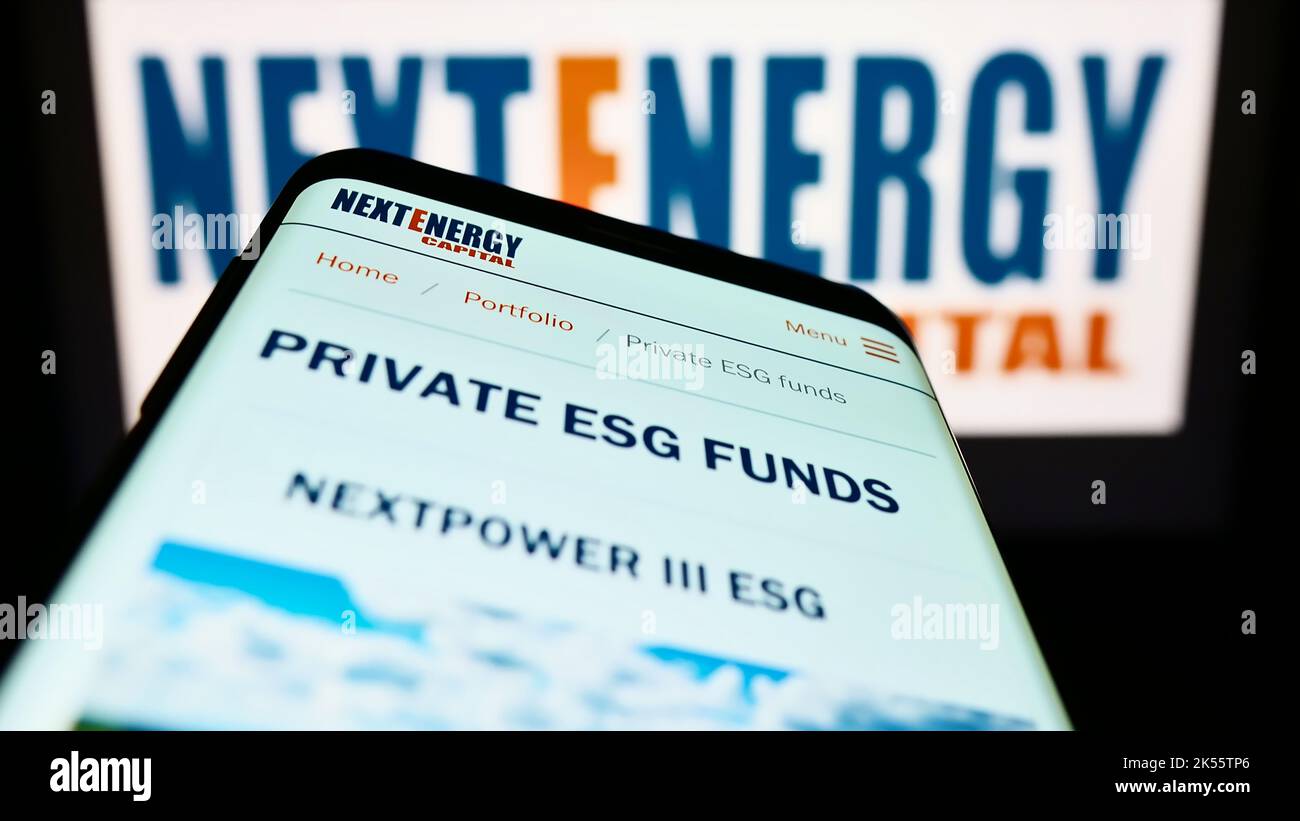 Mobile phone with website of British company NextEnergy Capital Limited on screen in front of business logo. Focus on top-left of phone display. Stock Photo