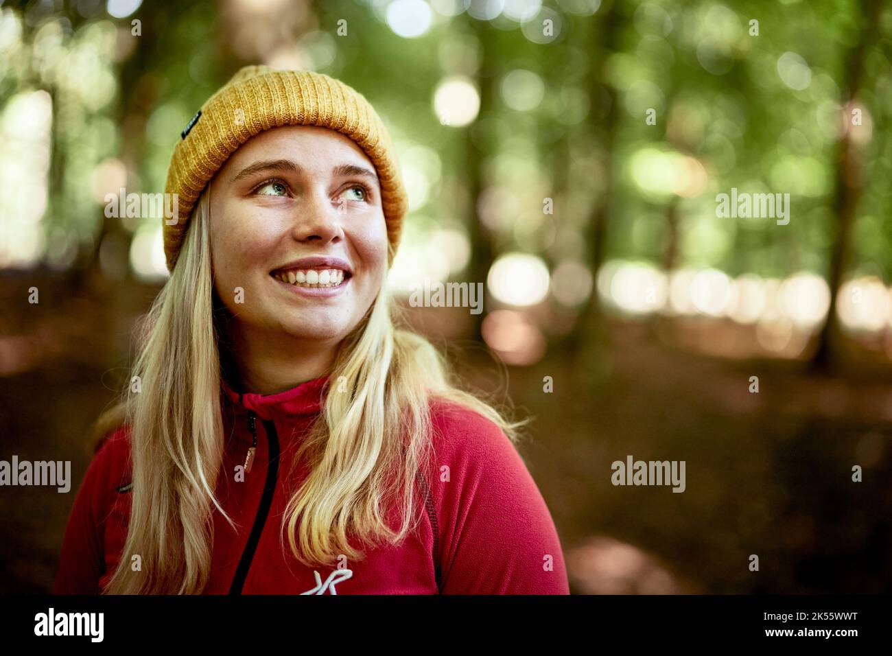 Young woman in red jacket walking in forest Stock Photo