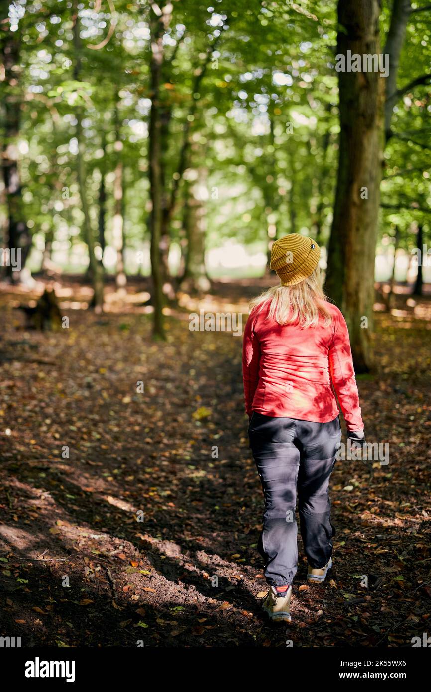 Young woman in red jacket walking in forest Stock Photo