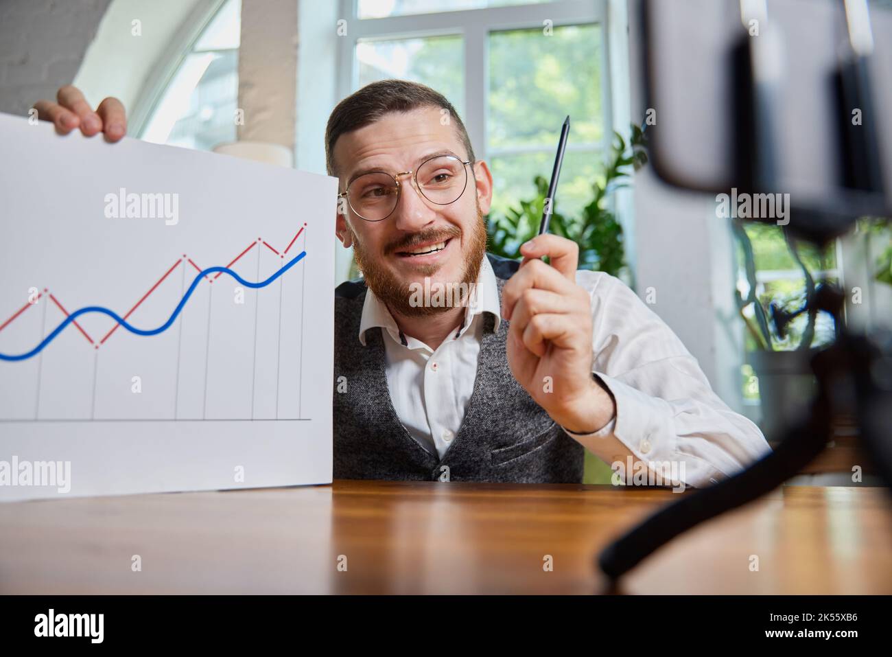 Close up male hands with pen pointing on business chart and mobile phone. People working with charts. Stock market exchange, businessman concept. Job Stock Photo