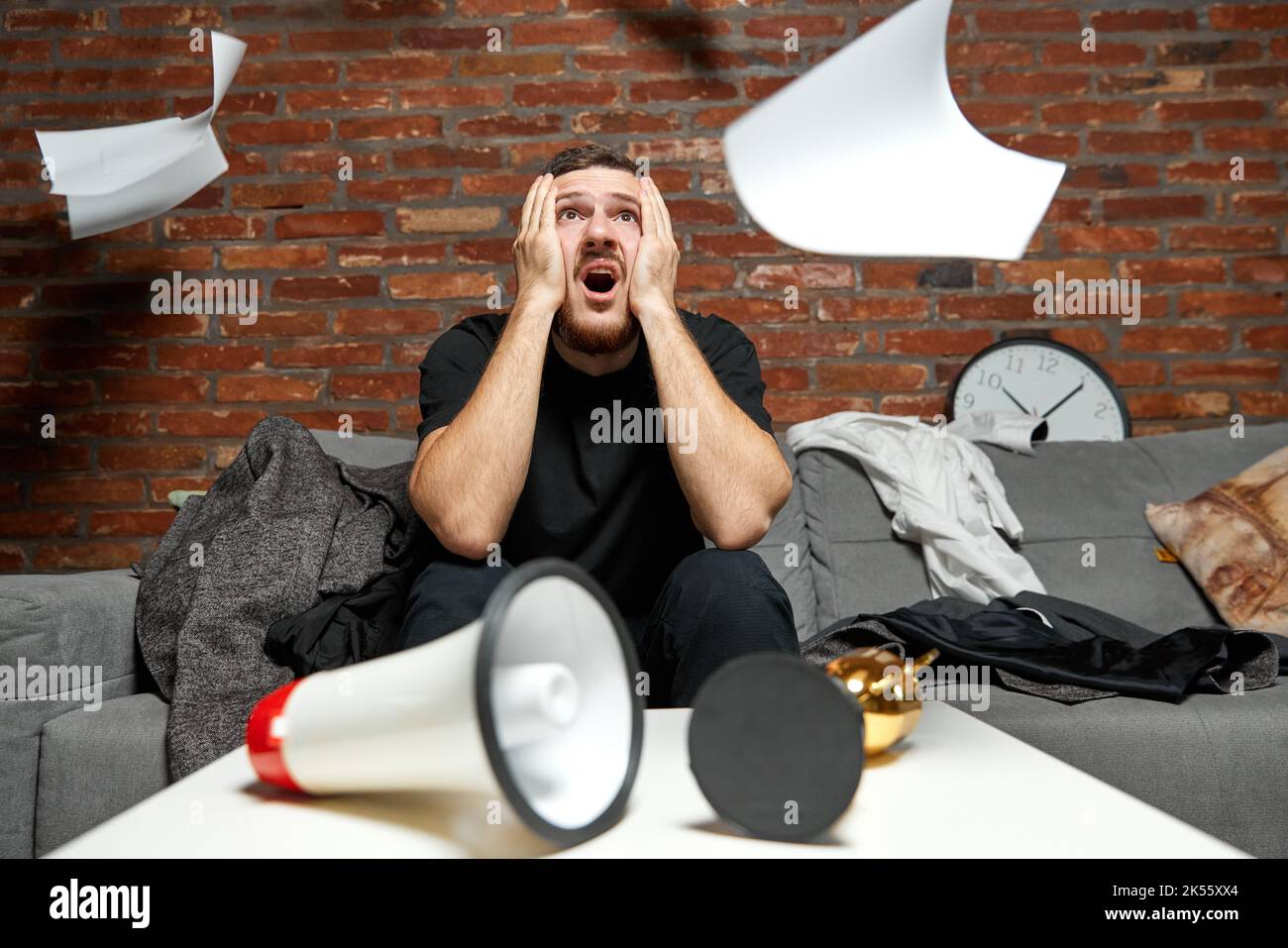 Stressed businessman or programmer working at home or office with anxiety checking time on clock, being in delay, deadline. Concentrated male Stock Photo