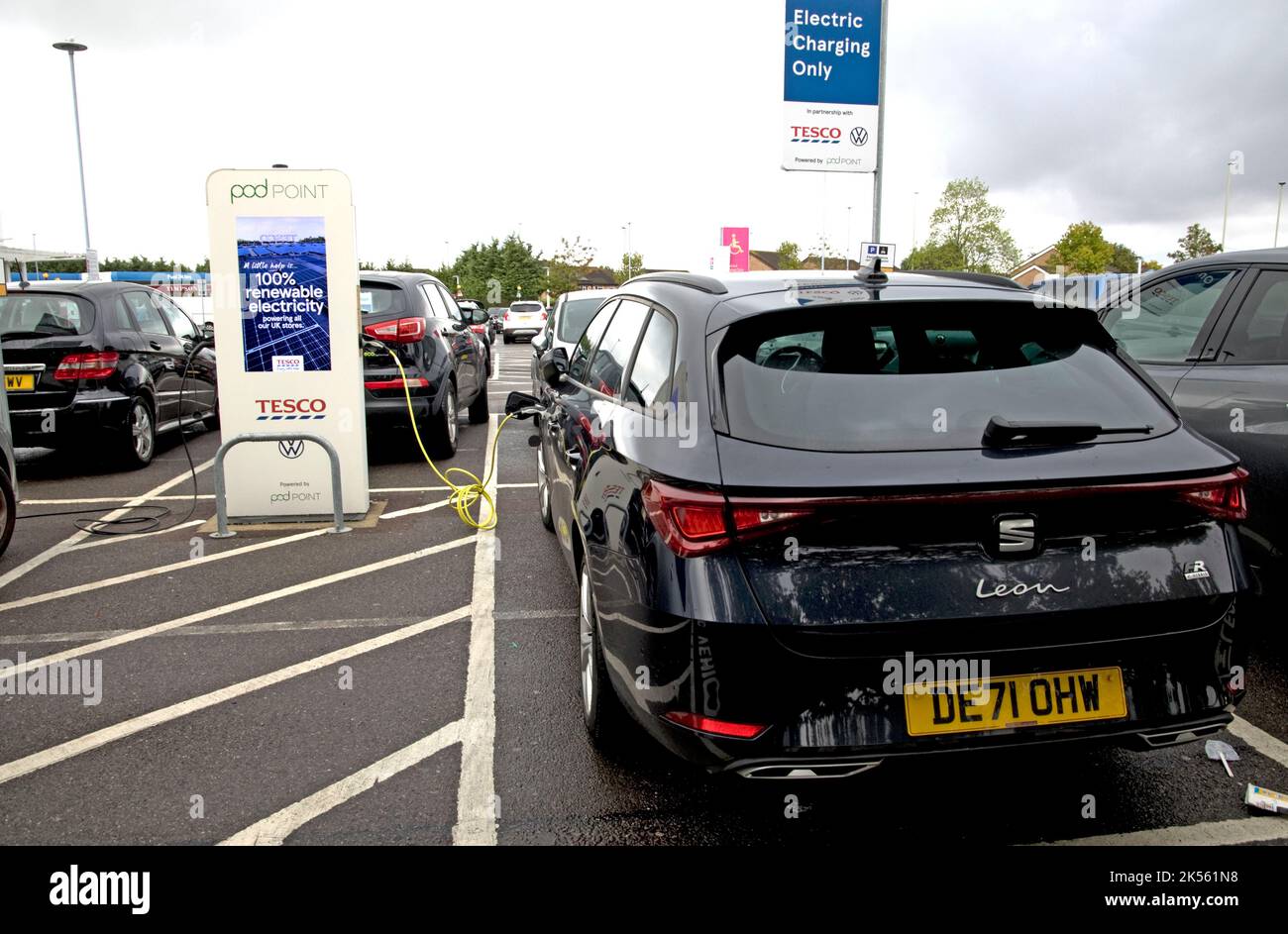Two electric vehicles charging at Tesco free 7kW charging points using 100% renewable electricity at Quedgely Gloucester UK Stock Photo