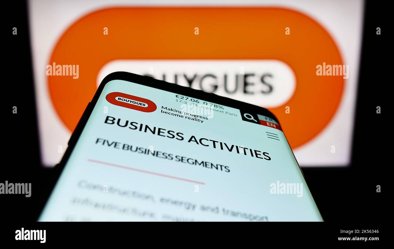 Smartphone with webpage of French conglomerate Bouygues SA on screen in front of company logo. Focus on top-left of phone display. Stock Photo