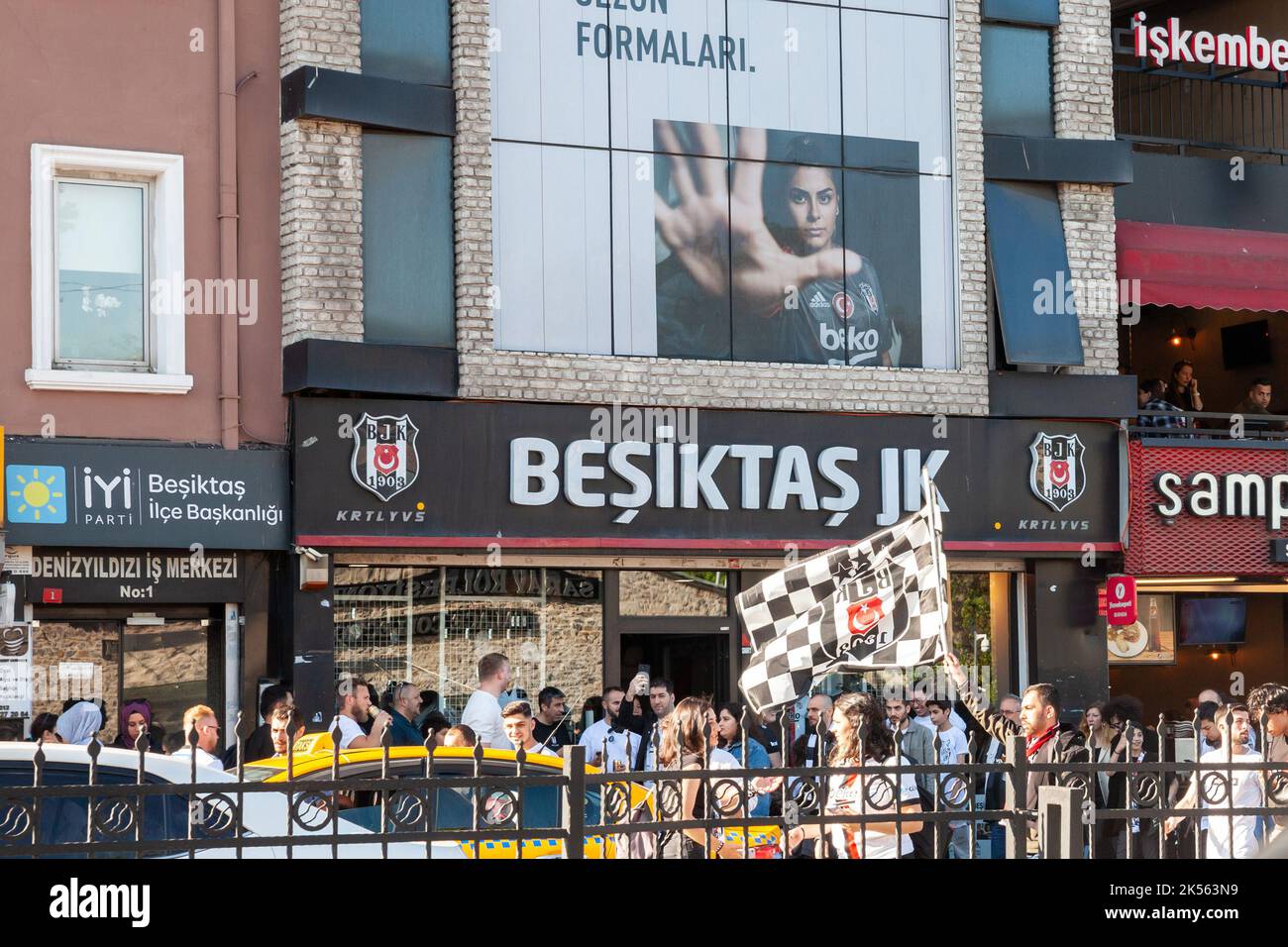 Picture of a sign with the logo of Besiktas on their official shop in Istanbul, Turkey, with supporters passing in front. Beşiktaş Jimnastik Kulübü, a Stock Photo