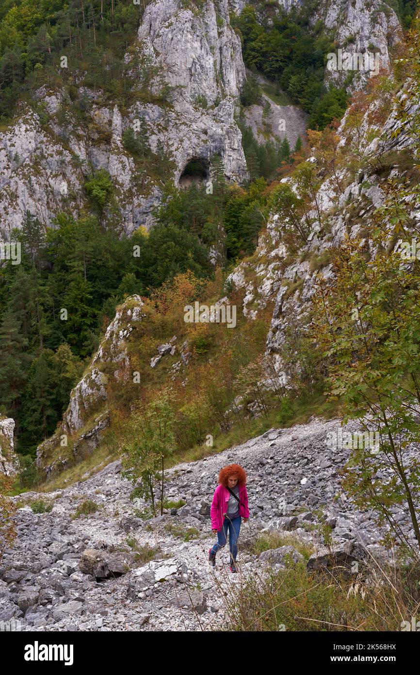 Tourist woman with curly hair with camera hiking on a steep trail in ...