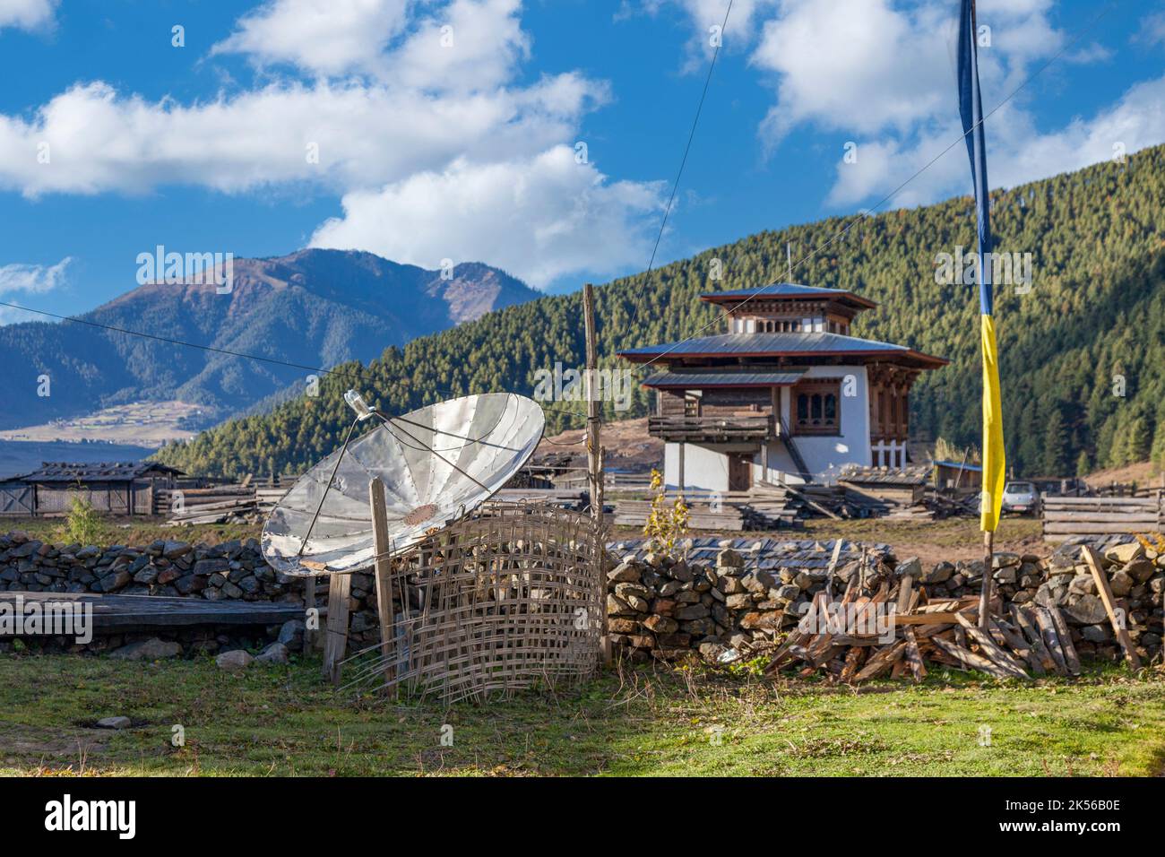 Phobjikha, Bhutan.  Satellite Dish in Foreground, Typical Middle-class Rural Farmhouse in Background,  Kikorthang Village. Stock Photo
