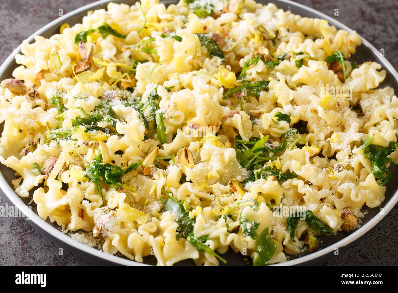Italian pasta with arugula, pistachios, parmesan cheese and lemon zest close-up on a plate on the table. horizontal Stock Photo