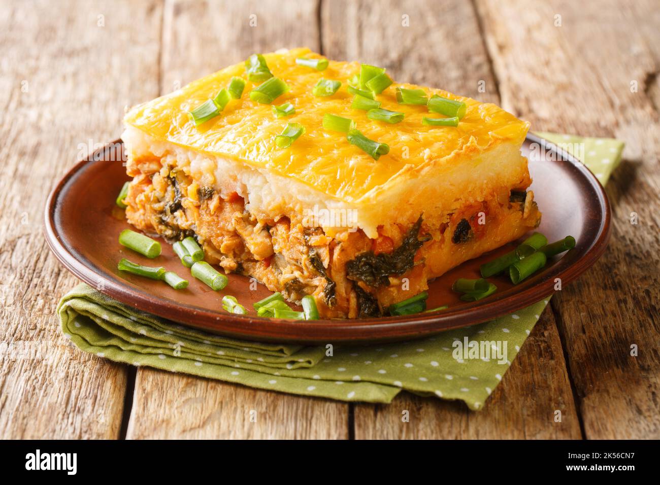 Portion of shepherd's pie of mashed potatoes with minced meat and vegetables on top with cheese close-up on a plate on the table. horizontal Stock Photo