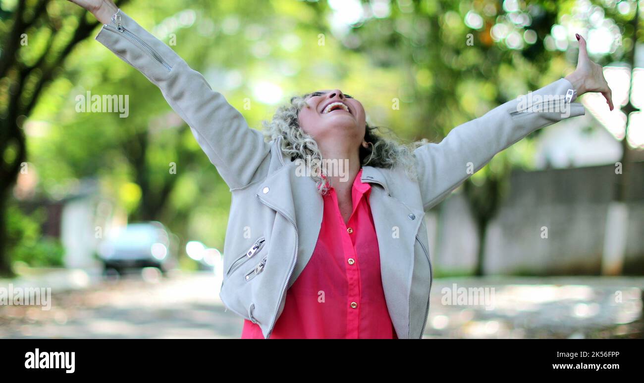 Ecstatic woman jumping with joy celebrating success outside in street ...