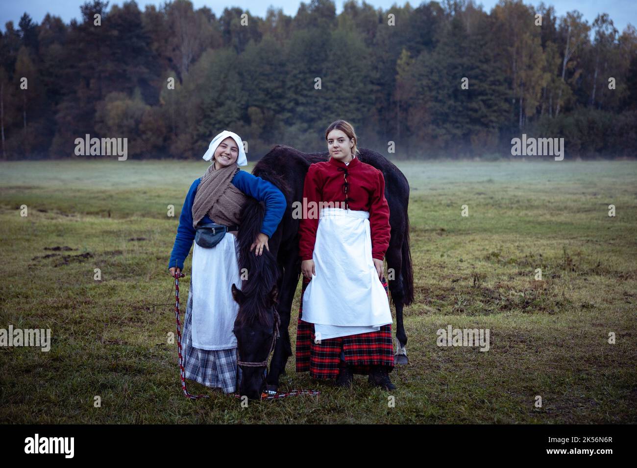 Two young women dressed as peasant women of the 17th century pose near ...