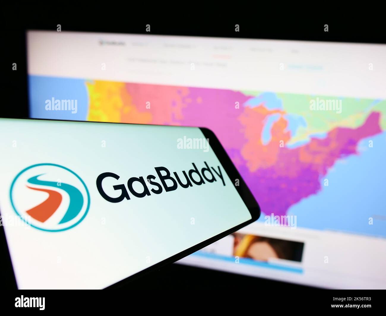 Cellphone with logo of American fuel pricing company GasBuddy LLC on screen in front of website. Focus on center-right of phone display. Stock Photo