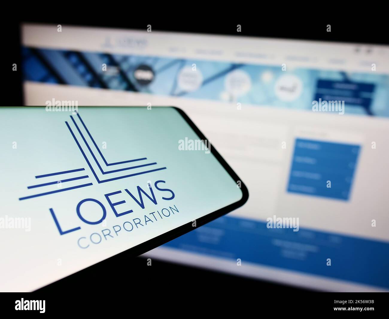 Mobile phone with logo of American conglomerate Loews Corporation on screen in front of company website. Focus on center-right of phone display. Stock Photo