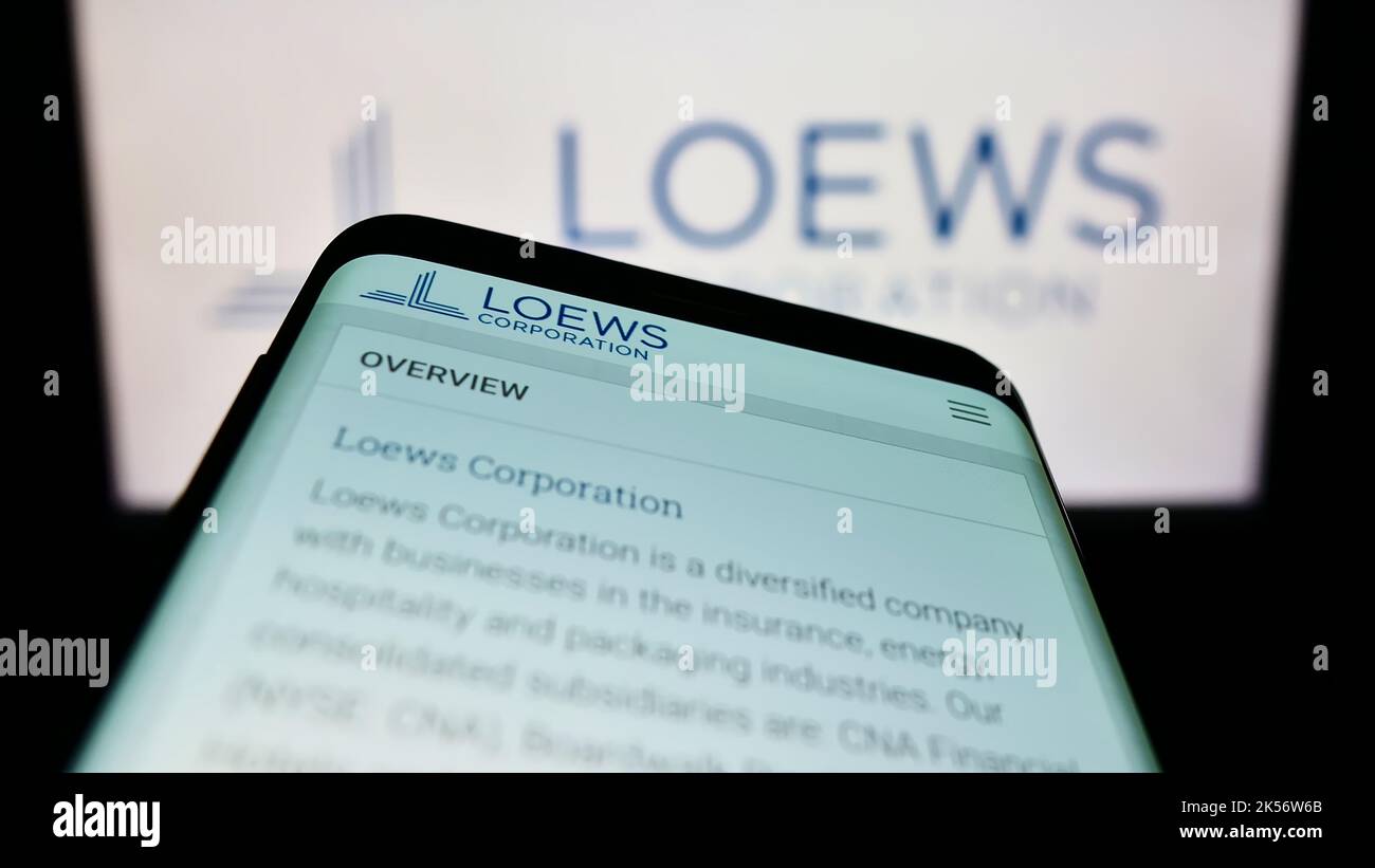 Smartphone with website of US conglomerate Loews Corporation on screen in front of business logo. Focus on top-left of phone display. Stock Photo