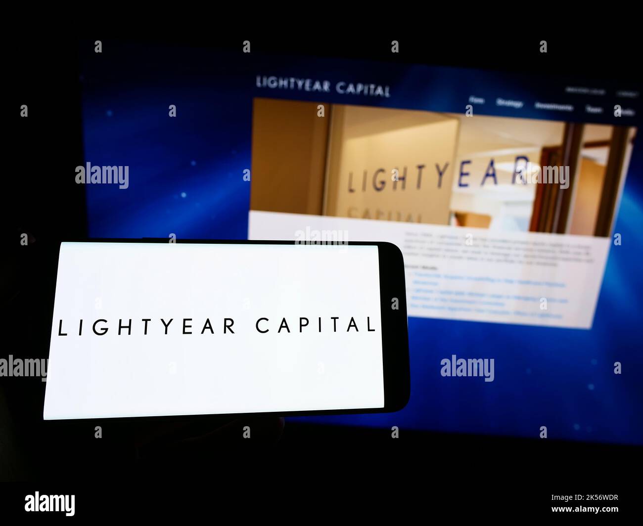 Person holding smartphone with logo of US private equity company Lightyear Capital on screen in front of website. Focus on phone display. Stock Photo