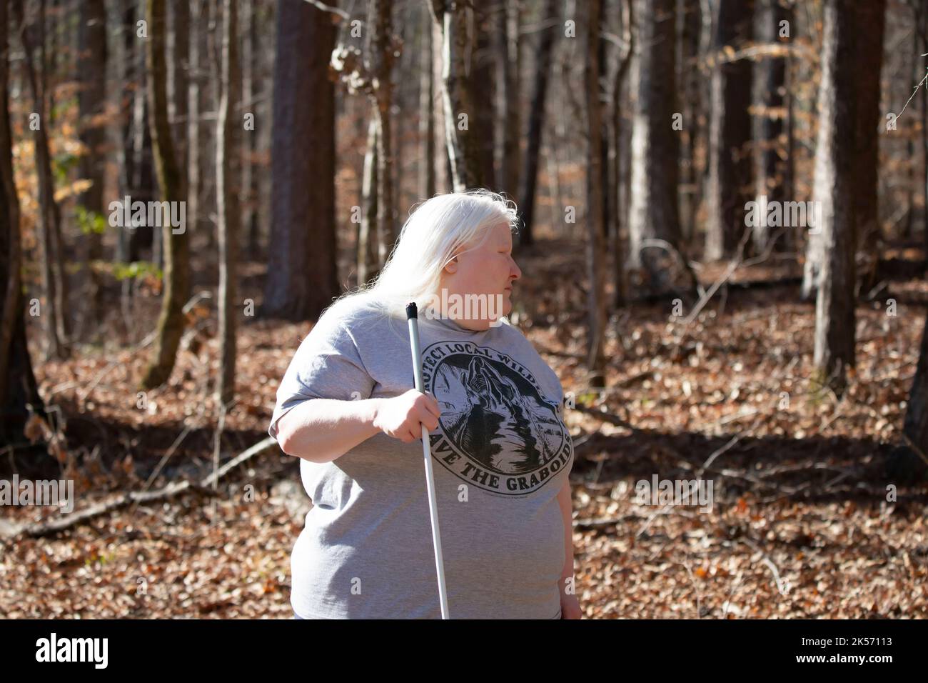 BLIND WOMAN ENJOYING A WOODED PARK, LOUISIANA/USA – FEBRUARY 19 2022: Blind woman looking around upset in a wooded park Stock Photo
