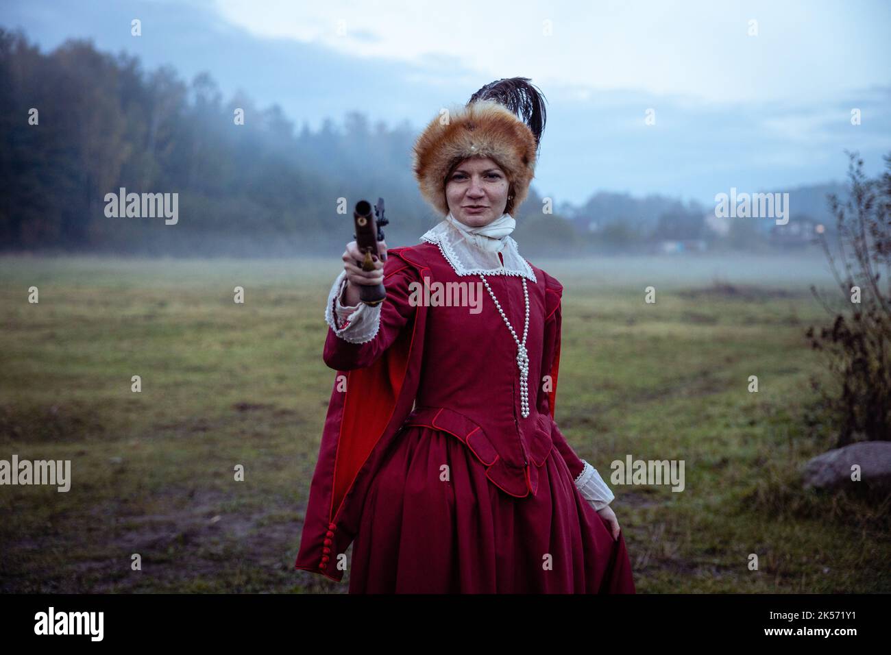 A woman in a 17th century red dress with a dueling pistol Stock Photo ...