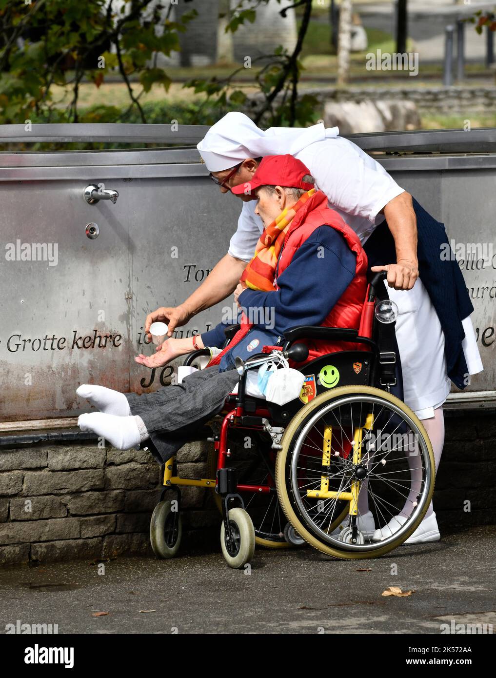 Lourdes, Hautes-Pyrénées, France. Christian pilgrims collecting Lourdes water that flows from the Grotto of Massabielle in the Sanctuary of Our Lady o Stock Photo