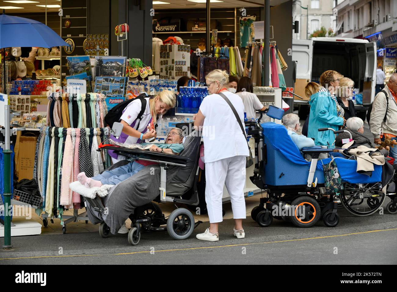 Lourdes, Hautes-Pyrénées, France. Carers with an invalide visiting the souvenir shops Stock Photo